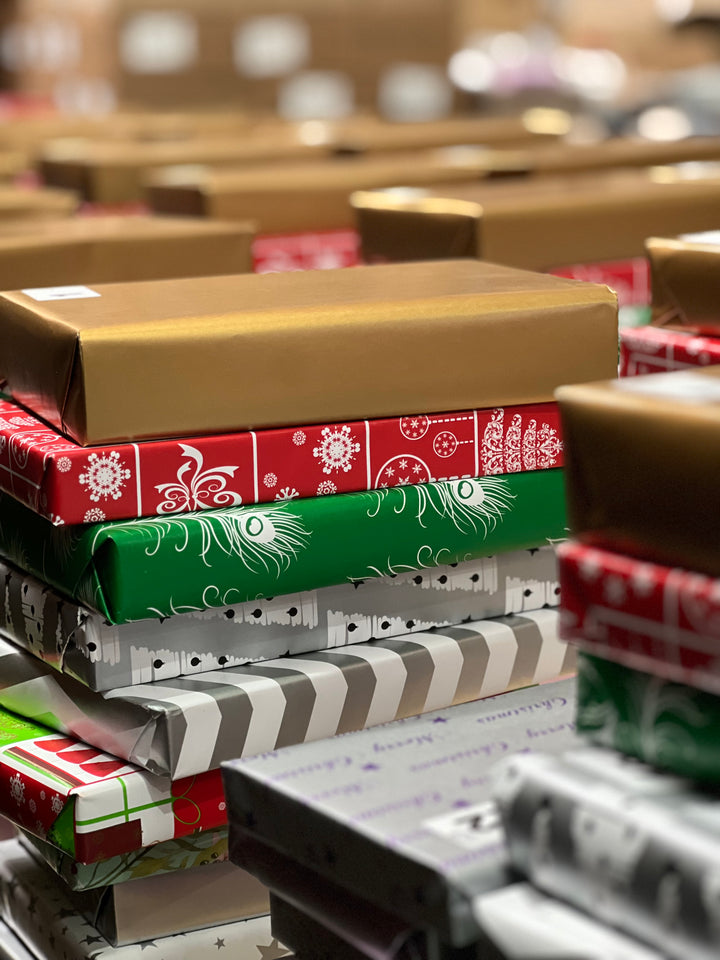 Image shows stacks of festively wrapped books being prepared for boxing up.